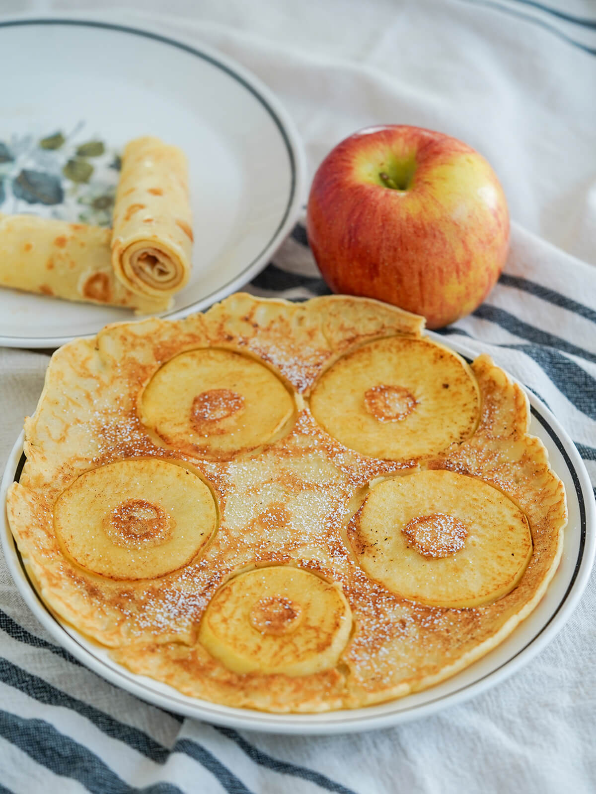 Dutch pancakes, pannekoeken, are wide and thin, and a blank canvas for both sweet and savory toppings. Comforting, adaptable and sure to be a favorite. Pannekoeken Dutch pancakes, front with apples and behind rolled up.