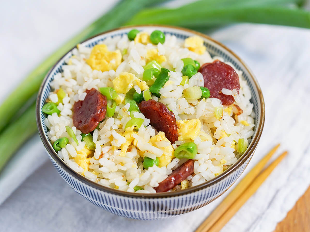 side view of bowl of Taiwanese fried rice with scallions behind bowl.