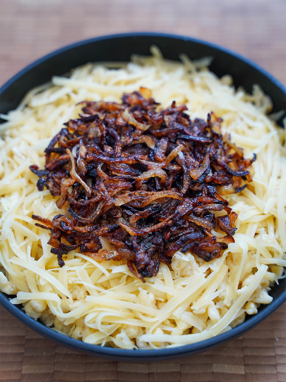 layered spaetzle and cheese, topped with onions, in skillet before melting in the oven.