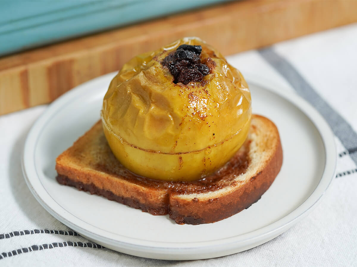 raisin stuffed baked apple on bread on a plate close up.